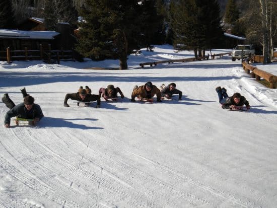 Bruce, Bill Hansen and others race sleds down the ranch driveway.