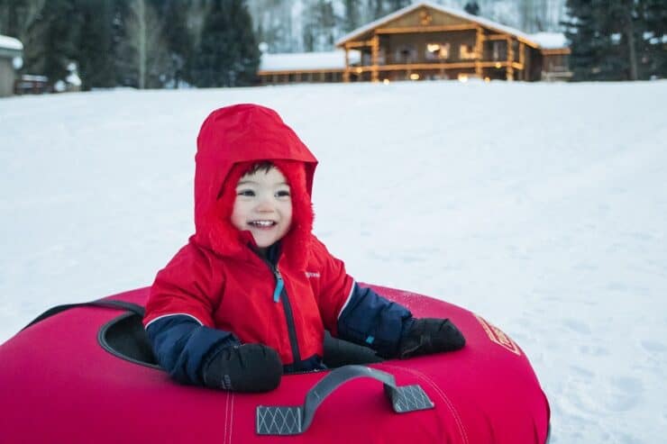 kid in snow tube enjoys the private tubing hill at C Lazy U Ranch in the winter