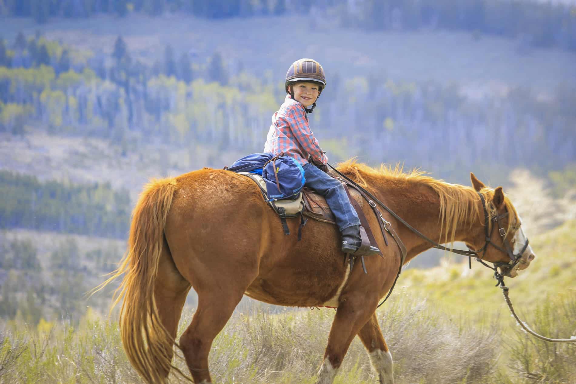 Young boy horseback riding at C Lazy U Ranch in Granby, Colorado.