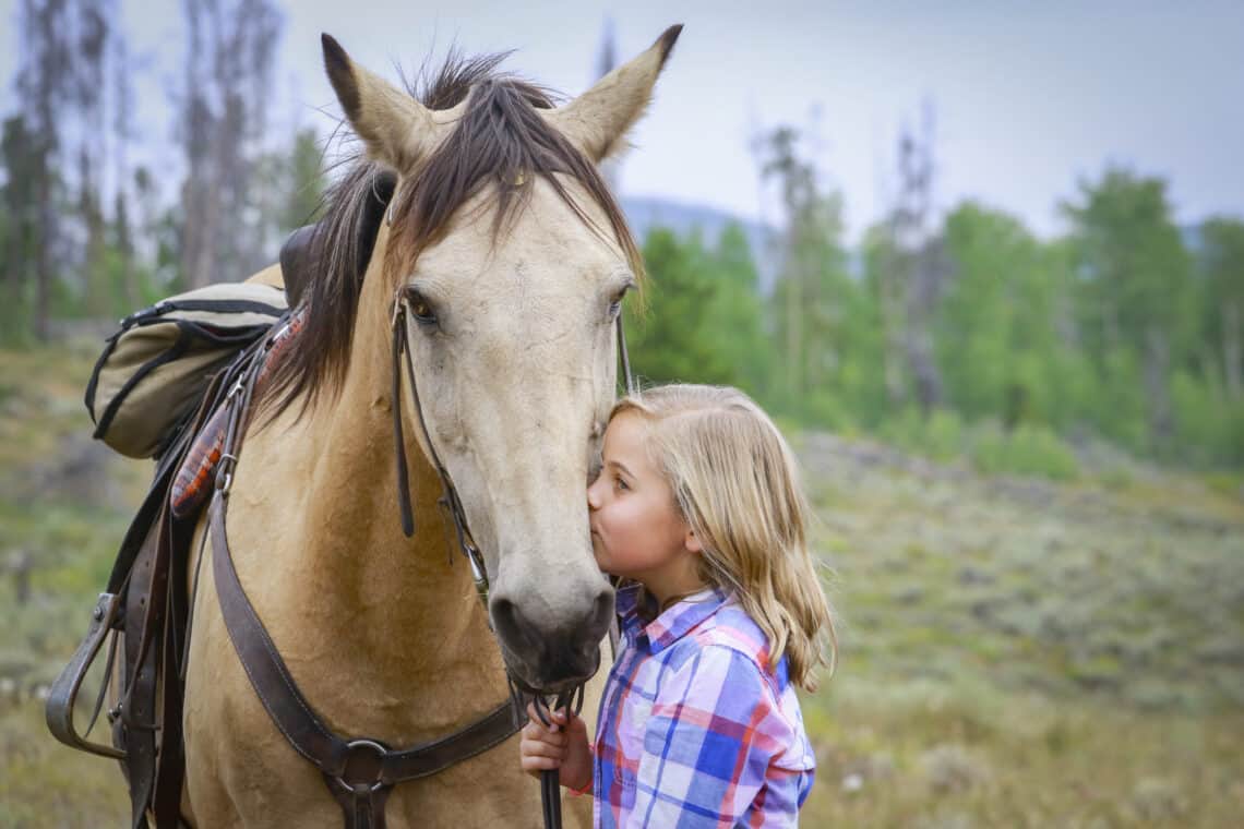 Young girl kissing horse at C Lazy U Ranch in Granby, Colorado