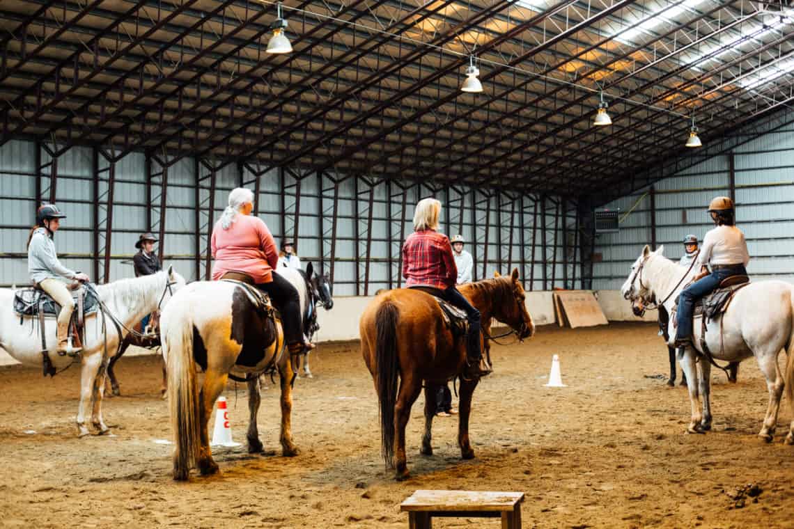 women on horses inside barn