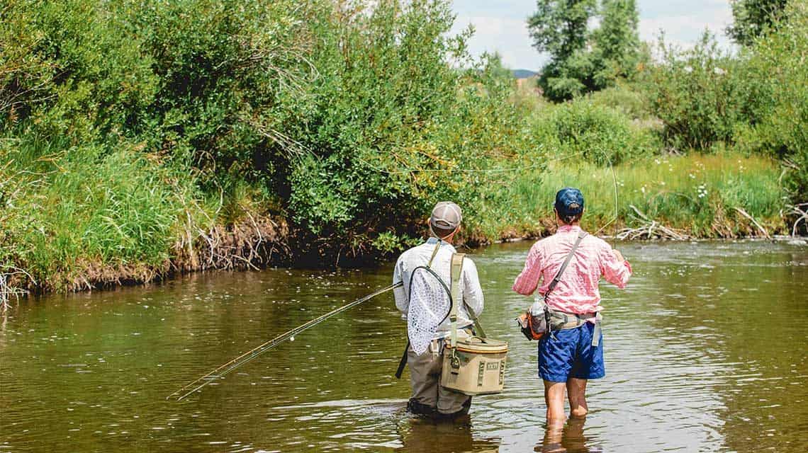 Guide holding extra rods while guest practices his fly casting.