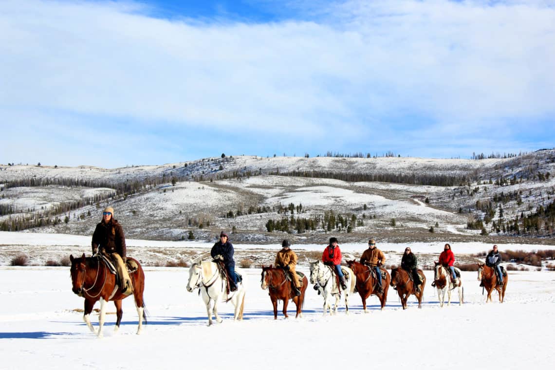 group of people horse back riding in the snow