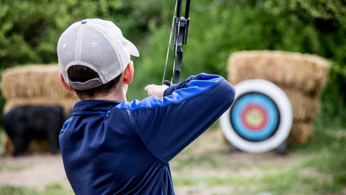 Young boy aims is bow at a target