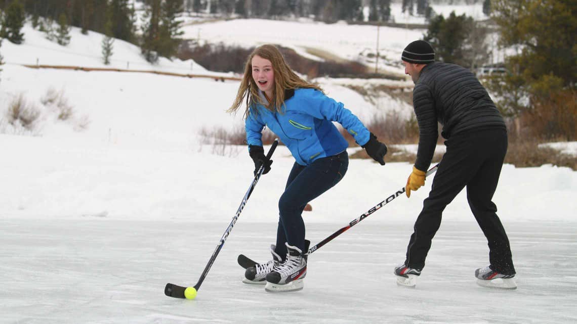 Two guests playing ice hockey on the frozen pond