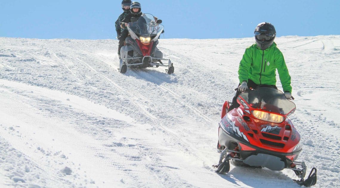 Snowmobiling in the winter sunshine at luxury dude ranch