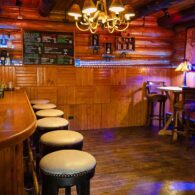 view of the C Lazy U bar showing the bar and barstools, plus the rest of the bar with tables and chairs