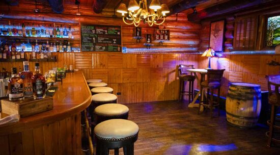 view of the C Lazy U bar showing the bar and barstools, plus the rest of the bar with tables and chairs