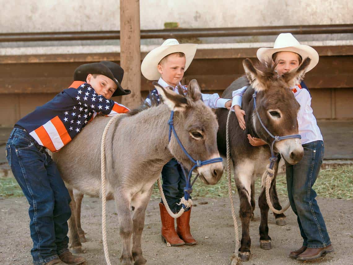 3 boys pose for a photograph with the ranch mascots: Petely and Tilly.