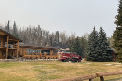 A fire truck on the morning of October 23, 2020. You can see Evergreen Cabin's foundation behind it. C Lazy U Ranch is incredibly grateful to the firefighters whose valiant efforts saved most of the ranch! a fire truck outside the Latigo Room