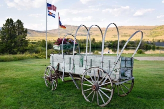 The old stagecoach sits on the lawn in front of the pond. Notice the sand volleyball court on the right.