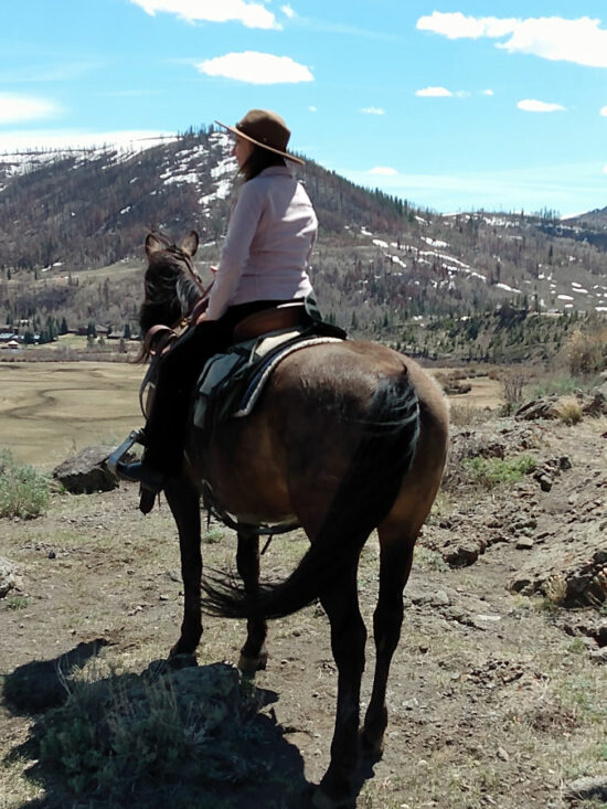 Cathy Woods on a horse in the mountains at C Lazy U Ranch in Granby, Colorado