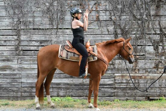 Cathy Wood on a horse doing the Eagle Arms pose during horse yoga at C Lazy U in Granby, Colorado