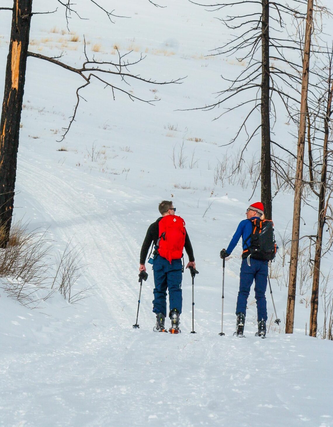 two men hiking uphill in thick snow