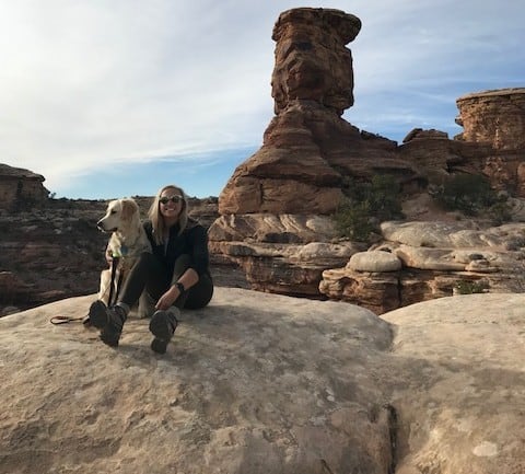 Woman posing with dog sitting on rocks