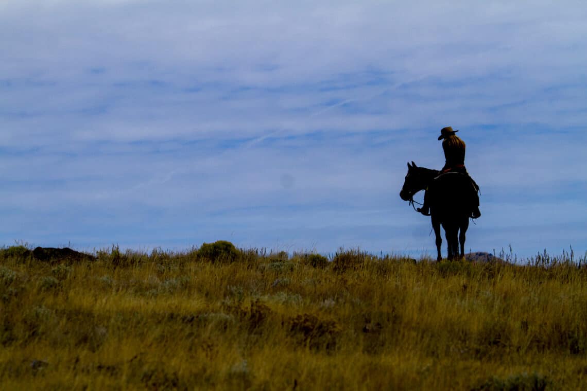 Silhouette of woman on horse at dusk at C Lazy U Ranch in Granby, Colorado