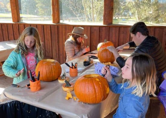 A family carves pumpkins together during their Fall Family getaway at the C Lazy U Ranch