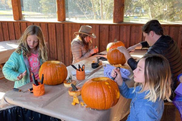 A family carves pumpkins together during their Fall Family getaway at the C Lazy U Ranch