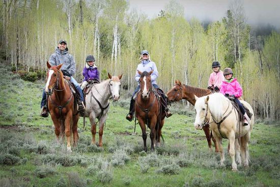 A family poses for a portrait while out on their horseback trail ride