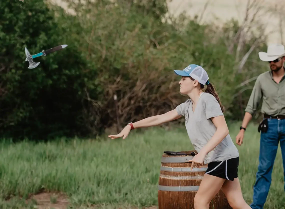 A woman throws a hatchet at the target during recreation time at C Lazy U Ranch