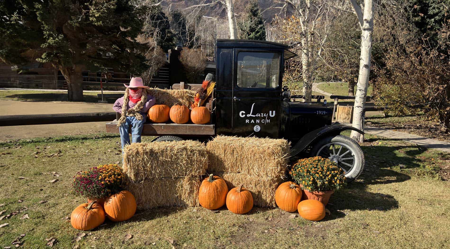 Fall decor at C Lazy U including the Model T truck, a scarecrow, pumpkins and straw bales