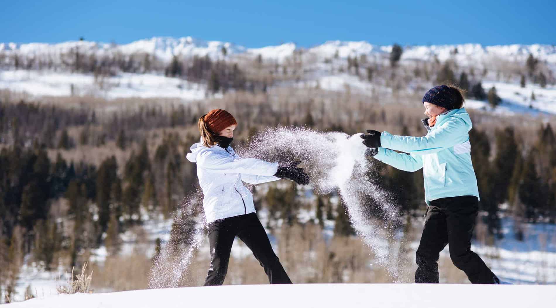 Two girls throwing snow at each other and having fun