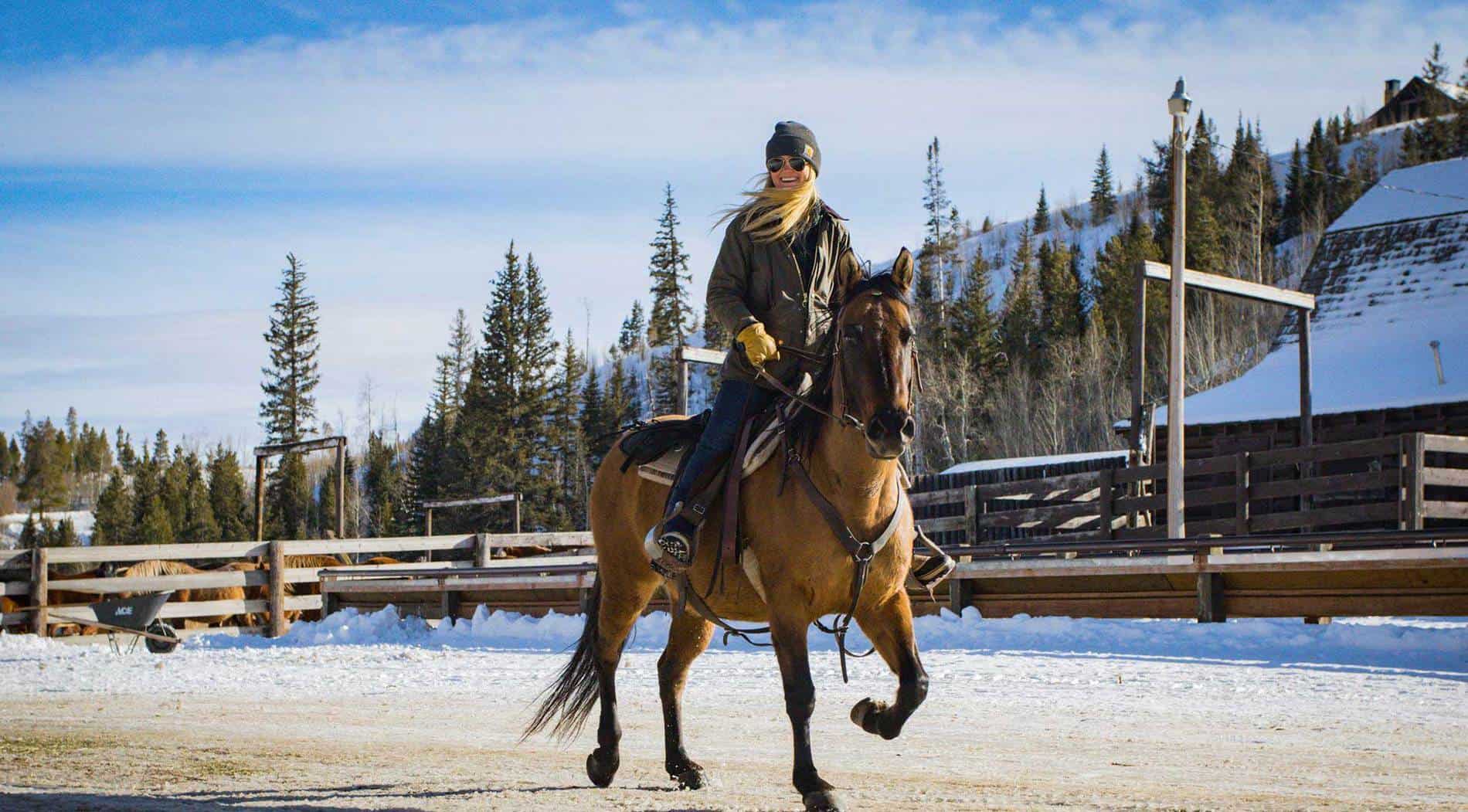 A rider trots her horse down the main road of the ranch