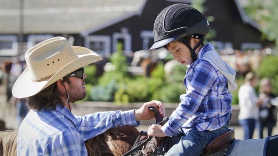 A child getting riding instructions from  a counselor at C Lazy U Ranch