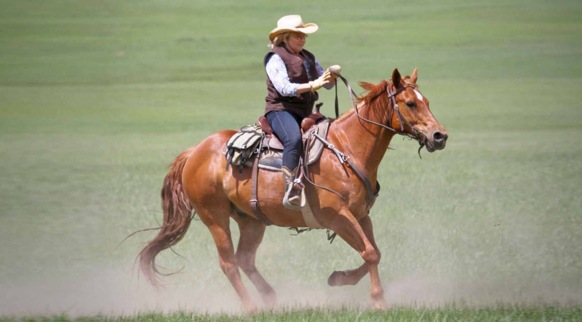 Woman rides her horse in a field at C Lazy U Ranch