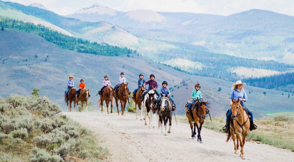 Children in the kids program at C Lazy U ride out on a trail ride with their counselors.