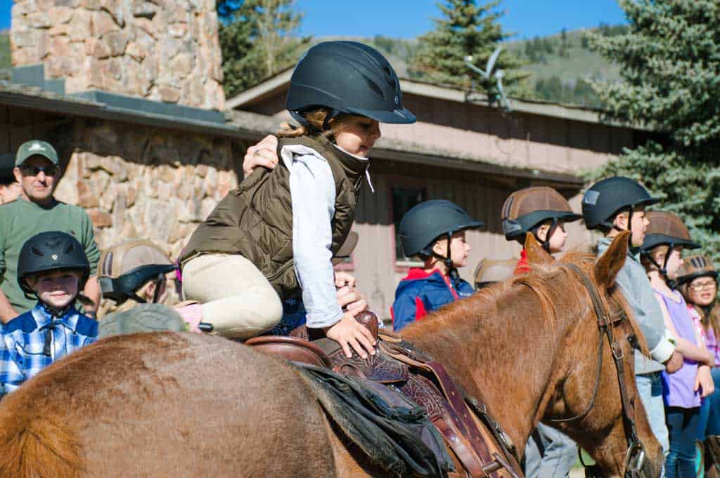 Kid getting on a horse at C Lazy U