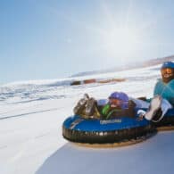 Mother and child snowtubing down the hill