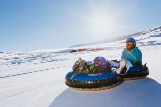 Mother and child snowtubing down the hill