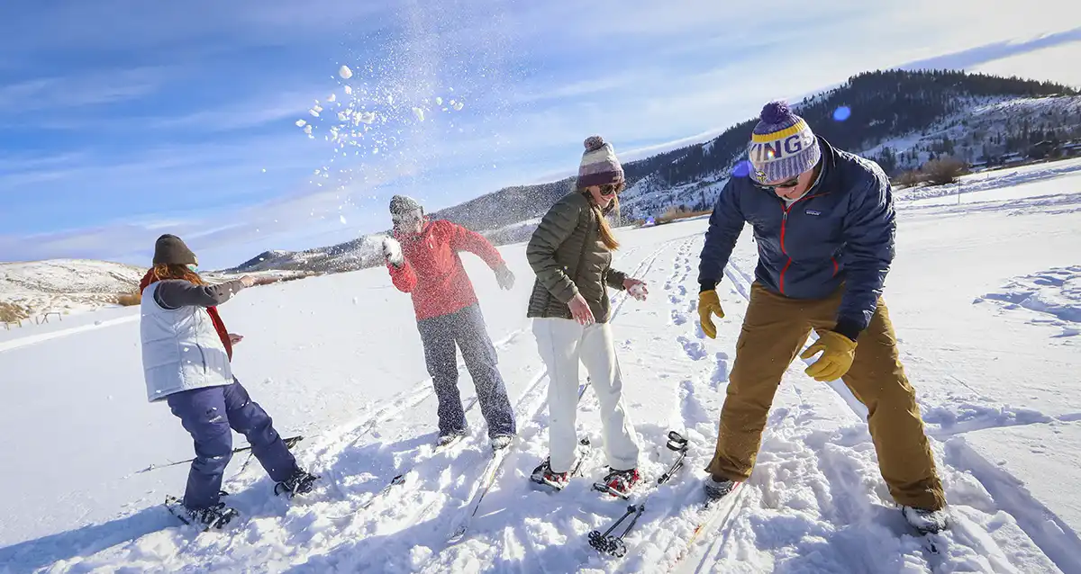 A family out for a cross-country skiing stops to enjoy a snowball fight