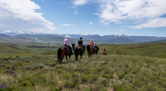 adults riding horses on C Lazy U's vast acreage