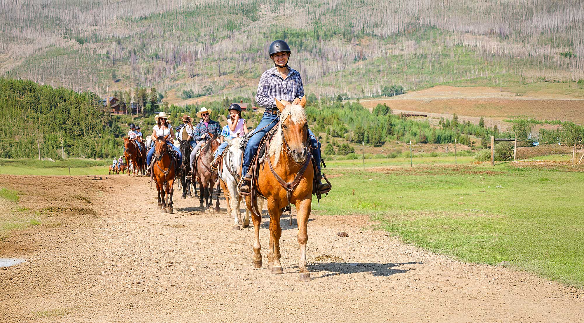 A wrangler leads families out on a trail ride
