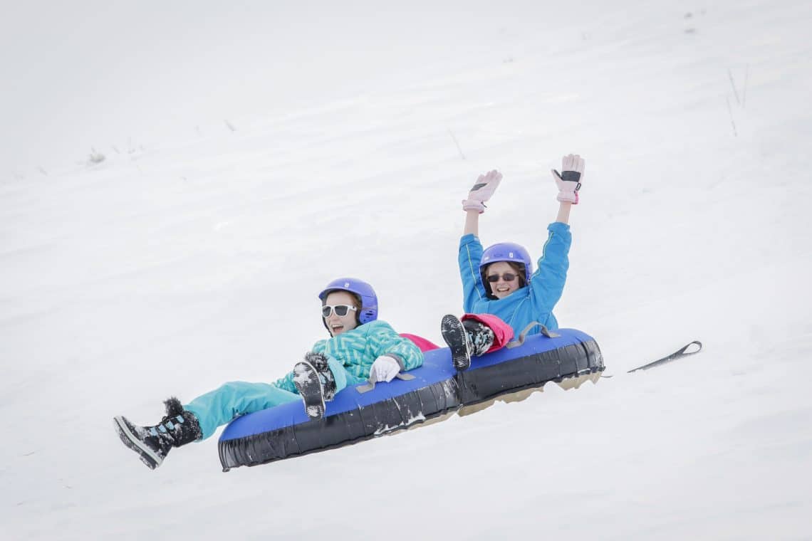 two people riding down snow in tubes