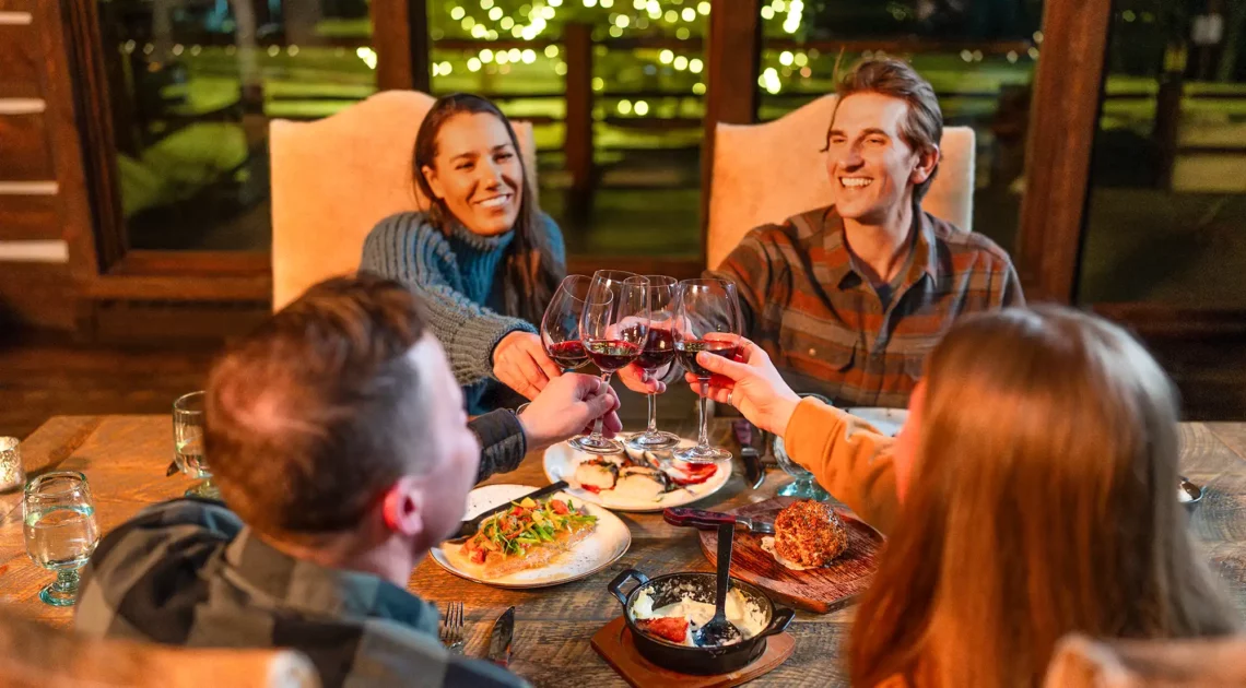 Friends toast with their wine glasses during a firelit dinner at C Lazy U ranch