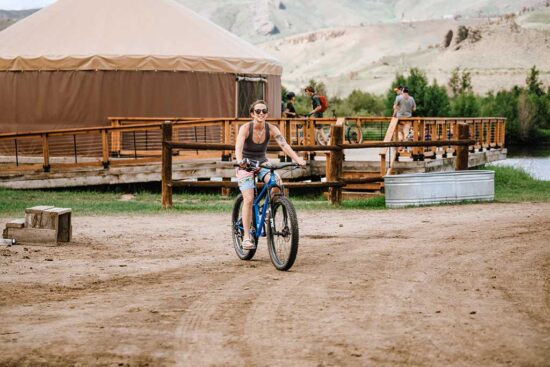 a woman rides a bicycle away from the activity yurt